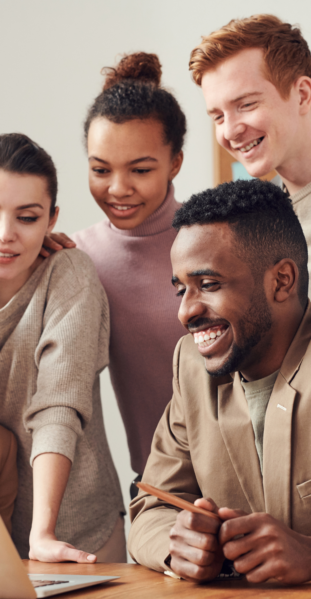 Equipe composé de plusieurs membres regardant un ordinateur en souriant